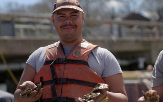 Man in a life vest hodling oysters