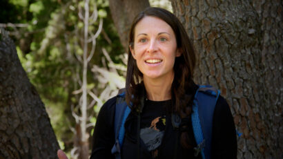 A woman with brown hair in a forest.