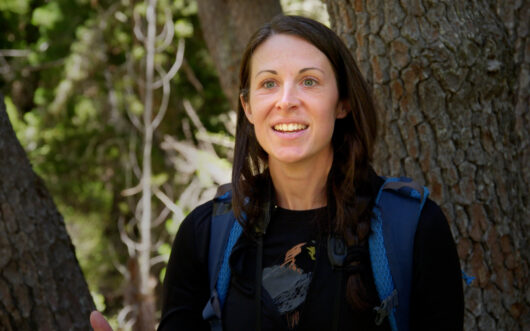 A woman with brown hair in a forest.