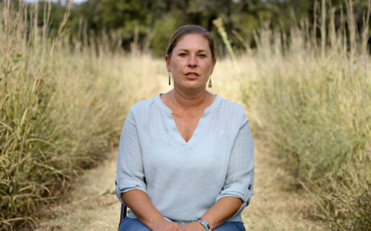 Jann Hayman, a member of the Osage Nation, sits in a tallgrass prairie.